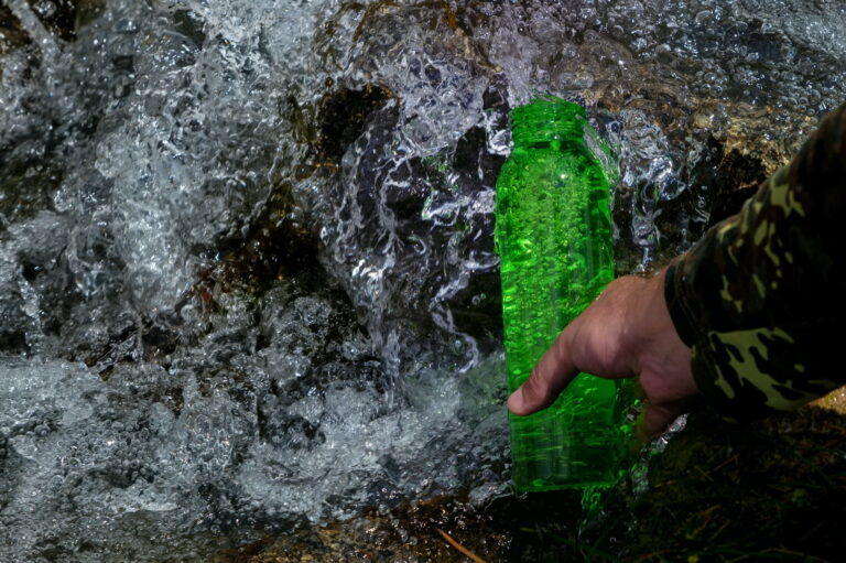 Outdoor travel water bottle. Pure natural water concept. Mountain spring
