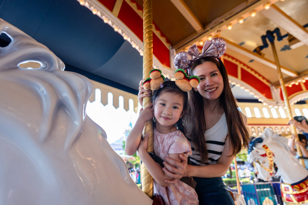 mother and adorable kid daughter riding a carousel at the Disney park